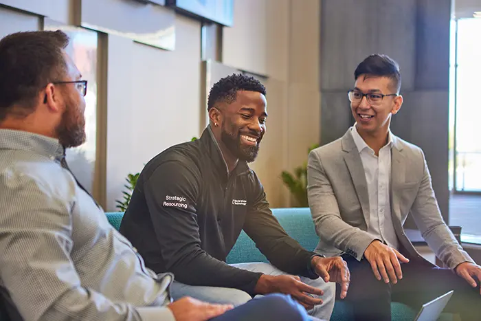 diverse men wwt employees sitting on couches smiling at informal meeting
