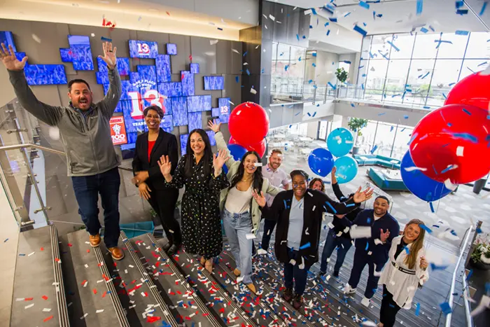 women and men standing on stairs with balloons and confetti in celebration