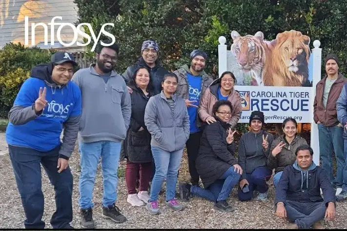 diverse men and women smile in front of the Carolina tiger rescue sign and trees 4