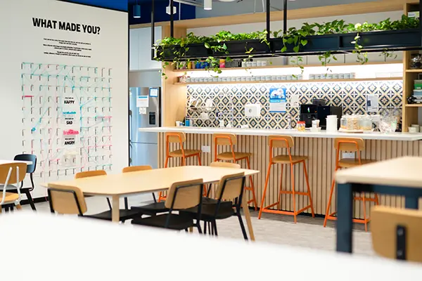 inviting cafeteria space with high and low tables and a feeling board for employees