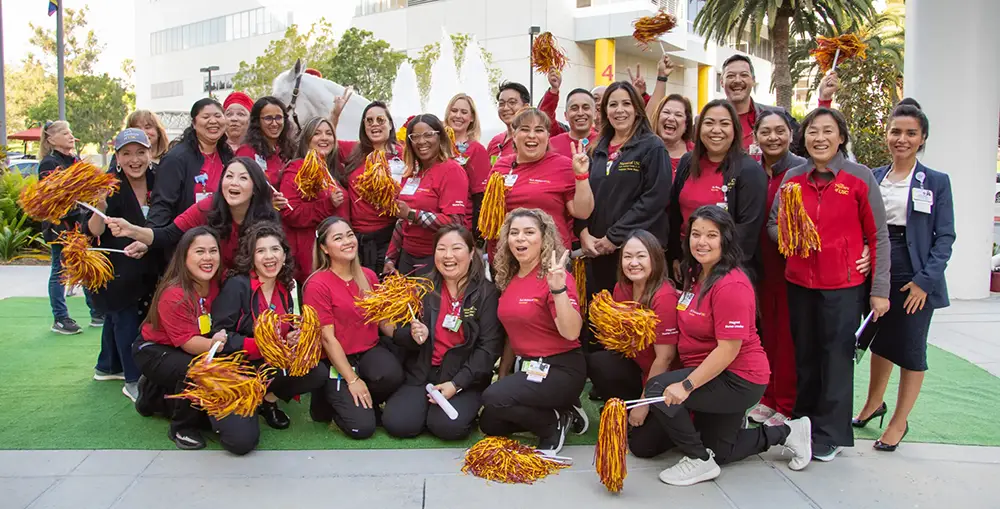Outdoor group of diverse men and women waving cheerleading pompoms with arms celebrating and cheering