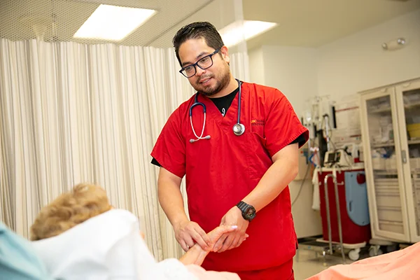 male nurse in a hospital setting hold the hand and checking the pulse of a patient lying in bed